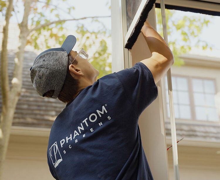 A Phantom Screens technician installing outdoor screens on a porch