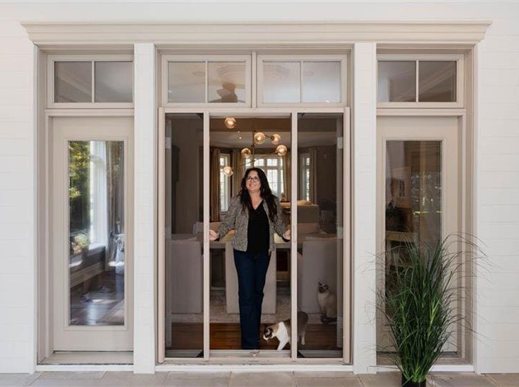 A person and their cat standing in open double French doors featuring mesh lock screen system, highlighting secure pet-proof screening and elegant architectural framing