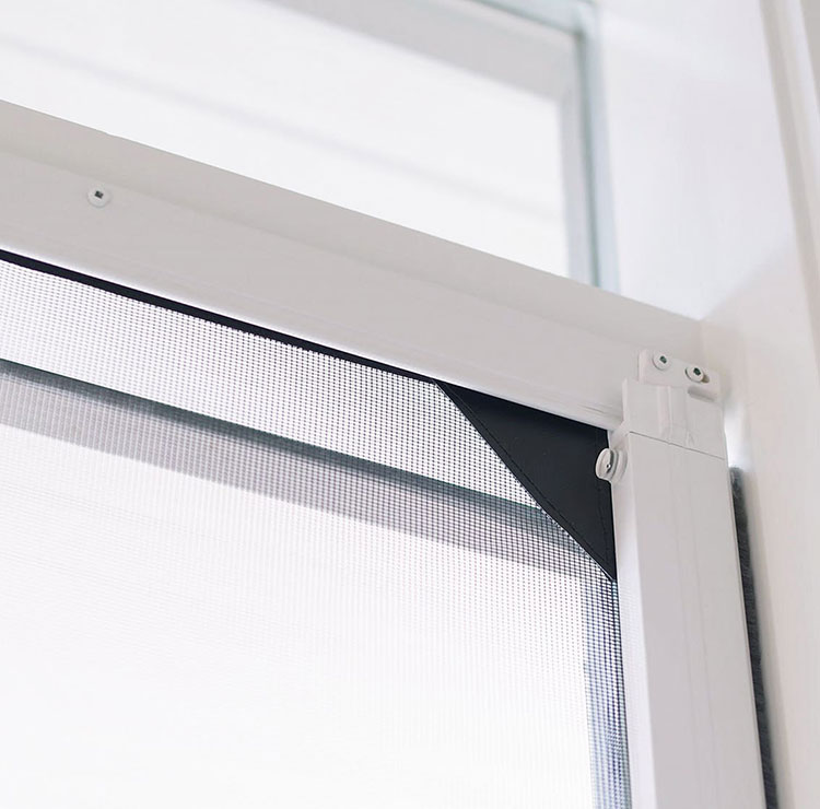 Detail shot of retractable screen door track and mounting system in white frame