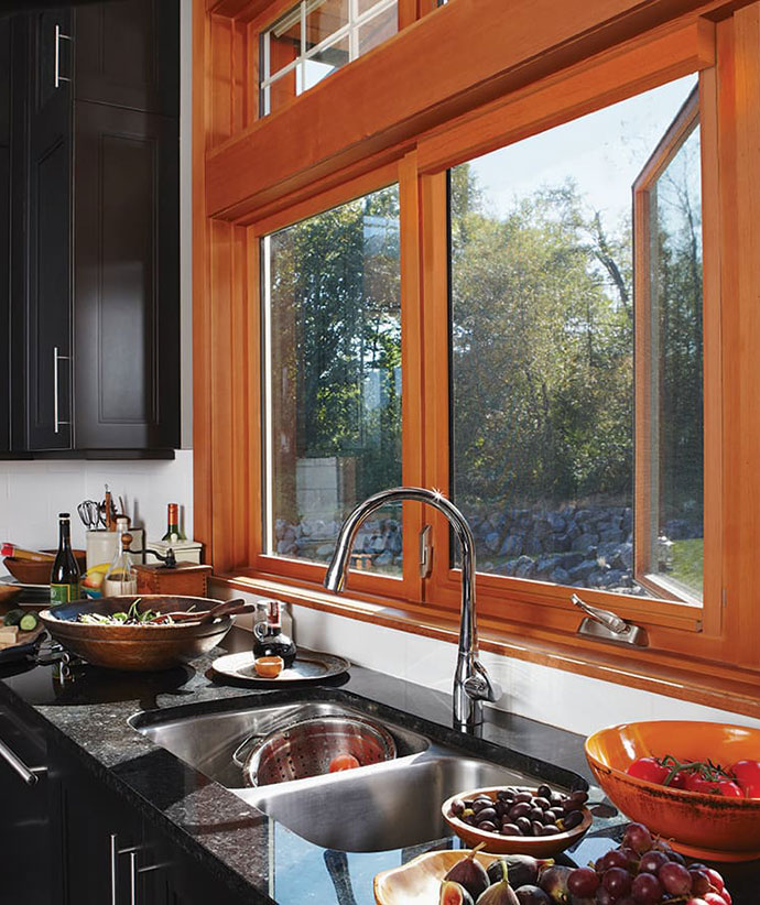 Modern kitchen featuring wood-trimmed windows with retractable screens above counter with fresh produce and cooking preparations